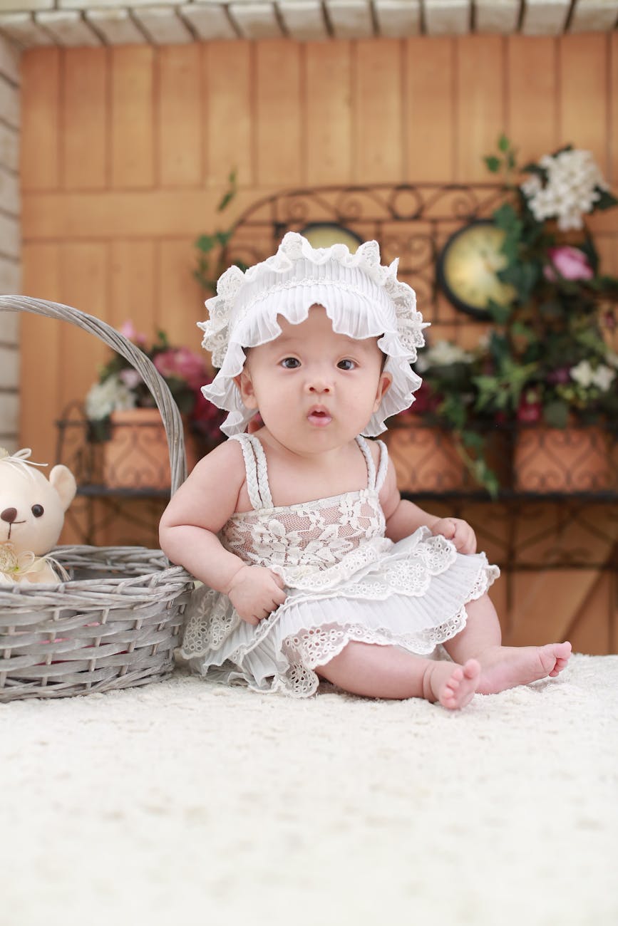 En bebis i vit klänning och vit hatt